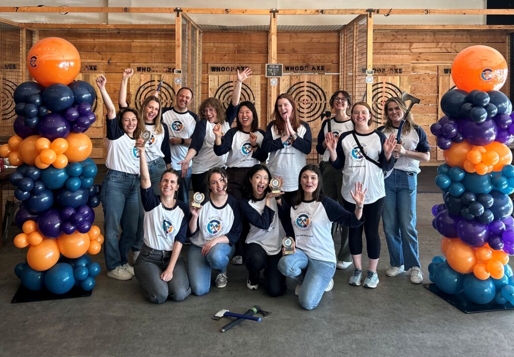 EVALCORP team members standing in a group smiling and cheering. Some are holding axes, or their trophies they have won