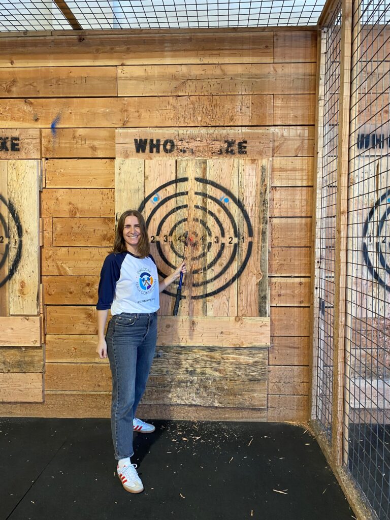 Mariana smiles with her axe in the bullseye of the target