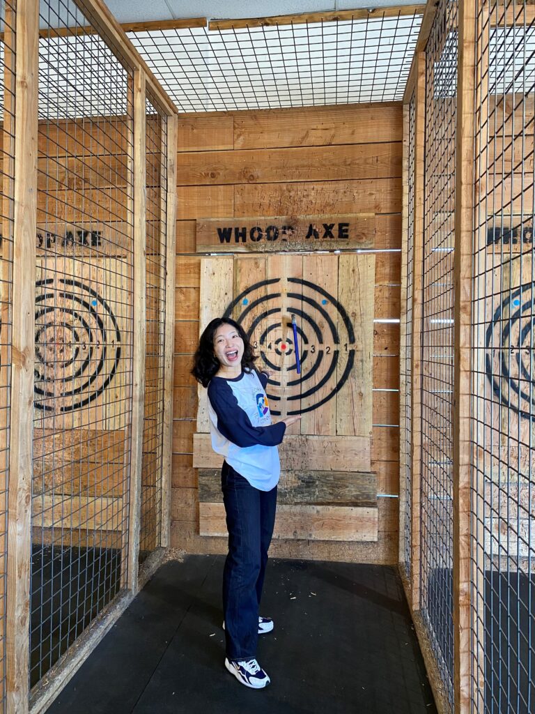 Stella smiles and poses with her axe on the target