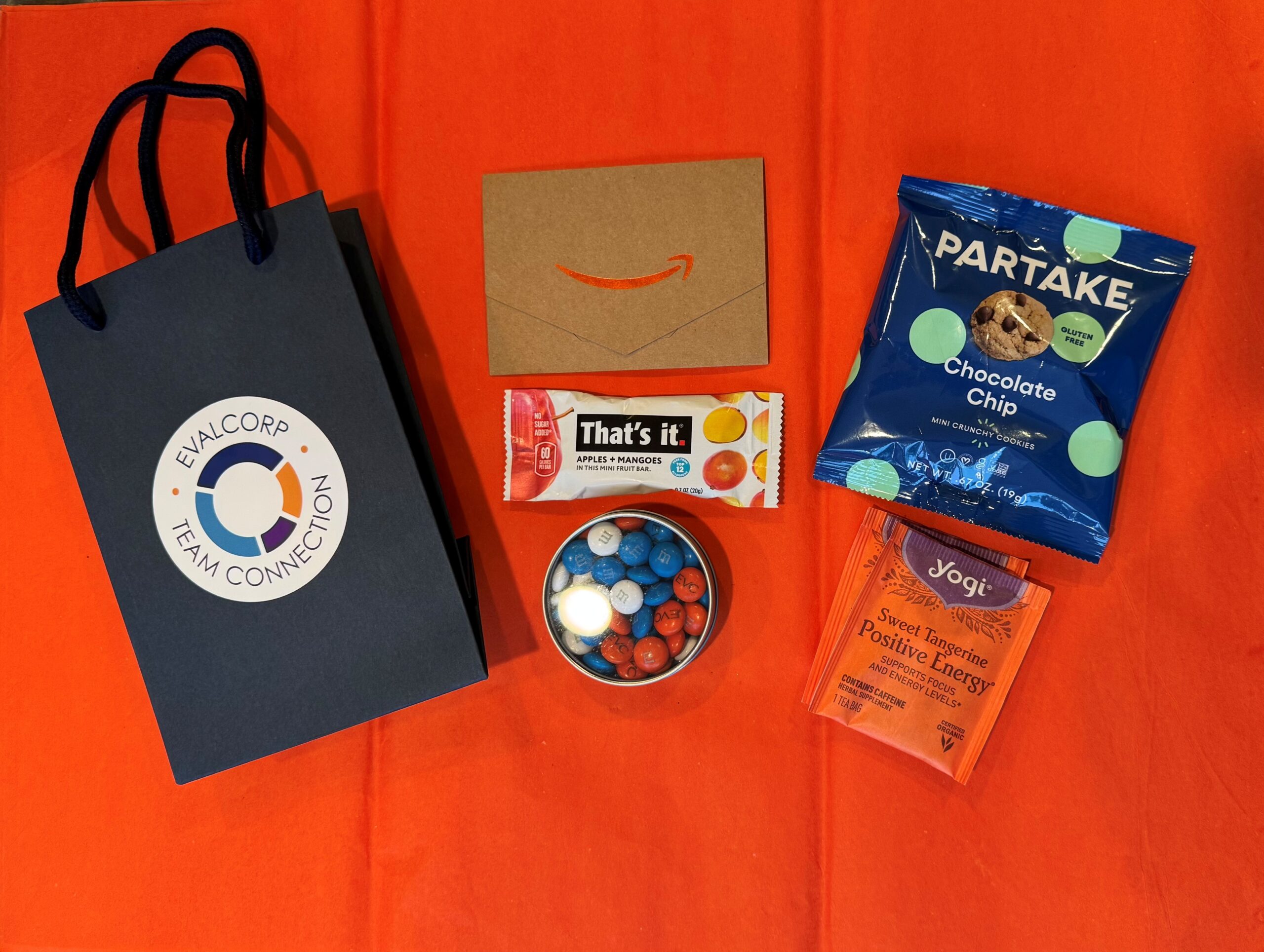 EVALCORP goodie bag including an Amazon giftcard, snack bar, branded m&m;s, partake cookies and tea