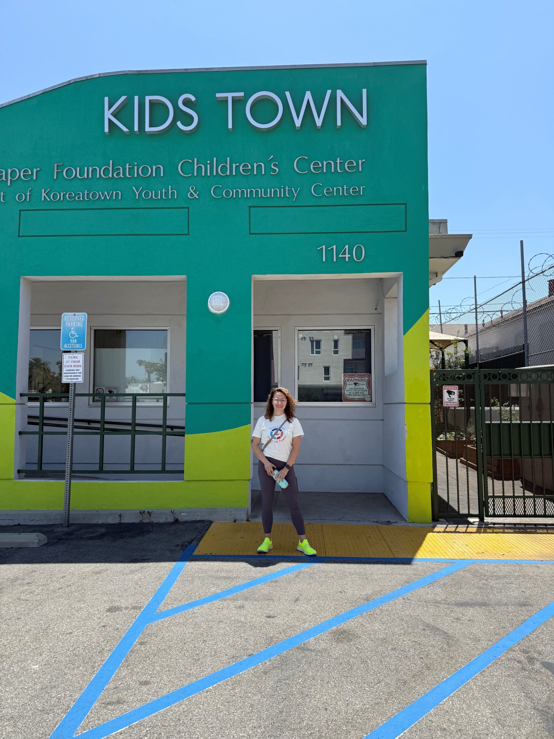 Alex smiling in front of the Kids Town Children's Center building