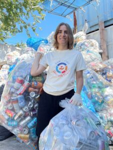 Photo of staff wearing t-shirt with "Service with Purpose" logo volunteering with a can redemption program