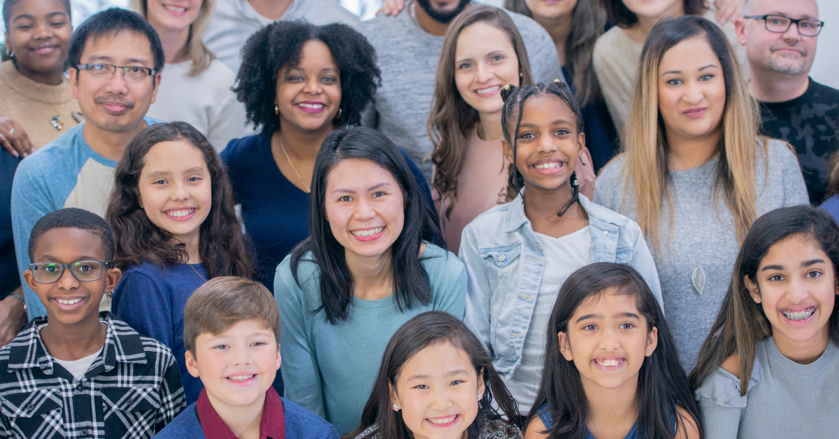 People of different ages, ethnicities, and cultural backgrounds standing next to each other smiling