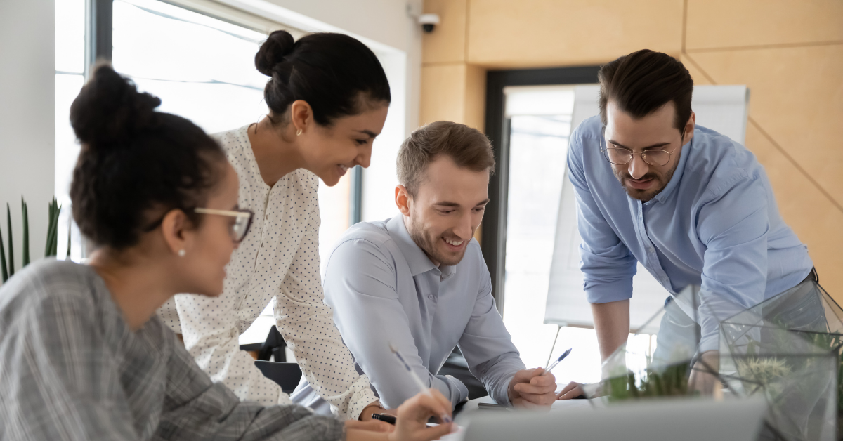 People smiling and sitting around a work desk looking at papers